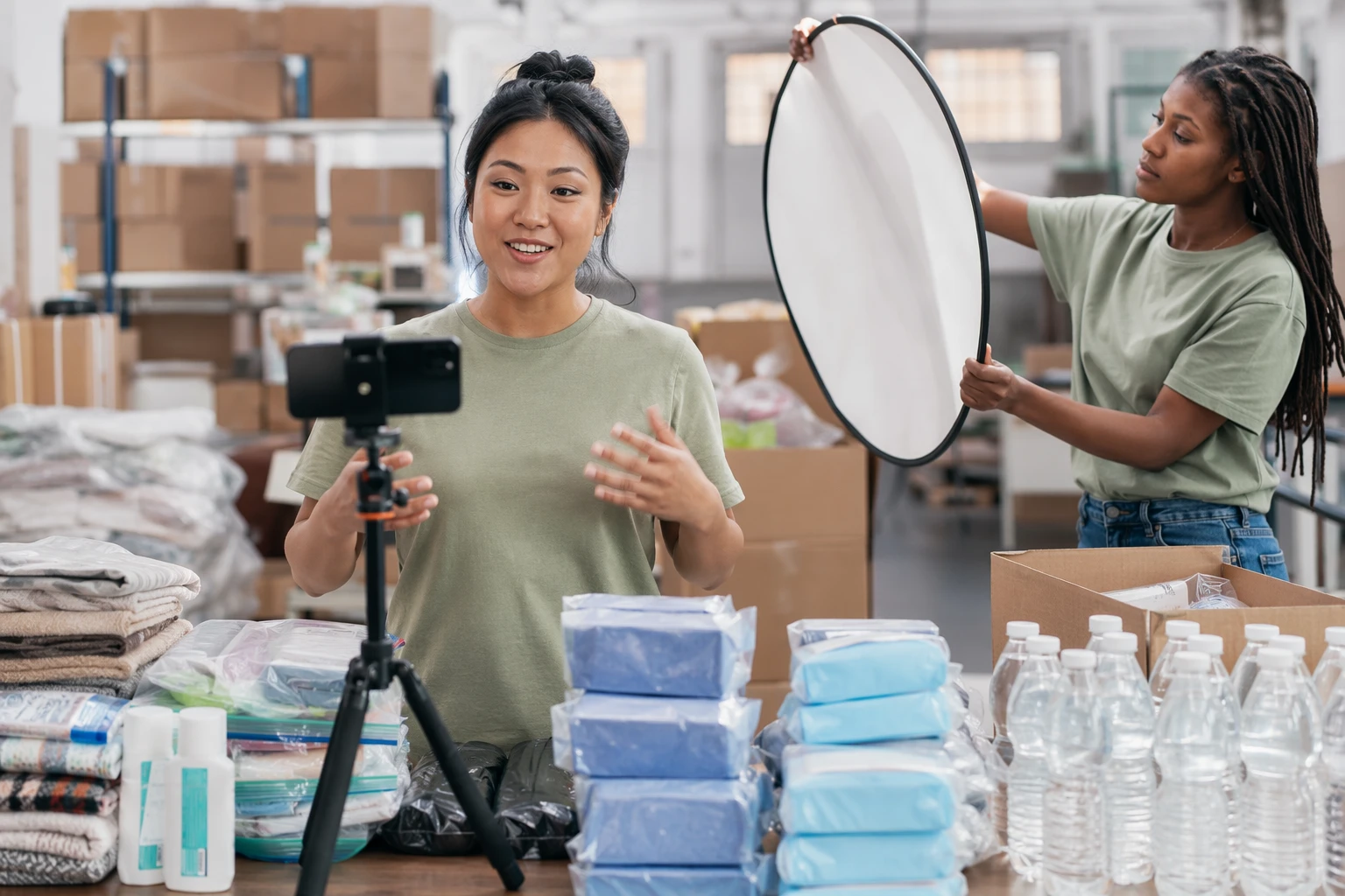 Program staff filming donor thank-you video beside relief supplies